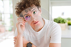 Young handsome man wearing glasses with hand on chin thinking about question, pensive expression