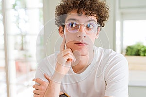 Young handsome man wearing glasses with hand on chin thinking about question, pensive expression