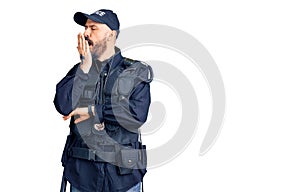 Young handsome man wearing police uniform bored yawning tired covering mouth with hand