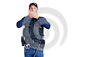 Young handsome man wearing police uniform shocked covering mouth with hands for mistake