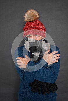 Young handsome man wearing in red hat and blue pullover feeling cold. Gas crisis concept