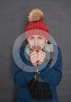 Young handsome man wearing in red hat and blue pullover feeling cold. Gas crisis concept