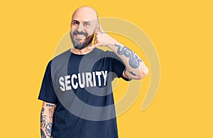 Young handsome man wearing security t shirt smiling doing phone gesture with hand and fingers like talking on the telephone