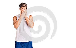 Young handsome man wearing sleveeless t shirt shocked covering mouth with hands for mistake