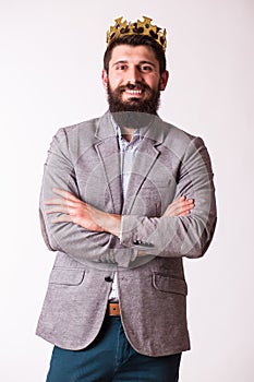 Young handsome man wearing suit and crown keeping arms crossed