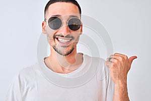 Young handsome man wearing sunglasses and casual t-shirt over isolated background pointing and showing with thumb up to the side