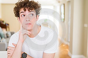 Young handsome man wearing white t-shirt with hand on chin thinking about question, pensive expression