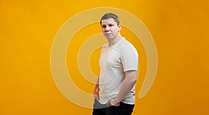 Young handsome man wearing white t-shirt looking at the camera over yellow studio background