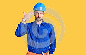 Young handsome man wearing worker uniform and hardhat looking stressed and nervous with hands on mouth biting nails