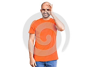 Young handsome man wering casual t shirt doing ok gesture with hand smiling, eye looking through fingers with happy face