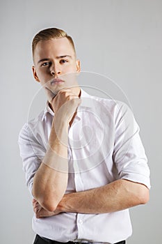 Young handsome man in white shirt touches his chin