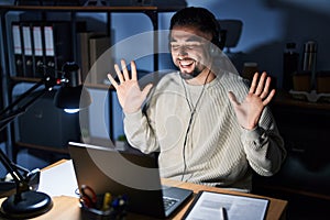 Young handsome man working using computer laptop at night celebrating mad and crazy for success with arms raised and closed eyes