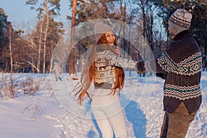 A young handsome man of European appearance and a young Asian girl in a park on the nature in winter