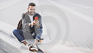 Young handsome men using smartphone in a city. Smiling student man texting on his mobile phone.