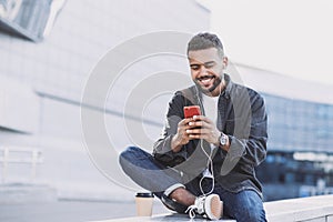 Young handsome men using smartphone in a city. Smiling student man texting on his mobile phone.