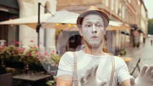 Young handsome mime is performing on street near cafe, denies, says certain no.