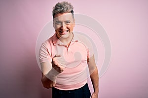 Young handsome modern man wearing casual pink t-shirt over isolated background angry and mad raising fist frustrated and furious