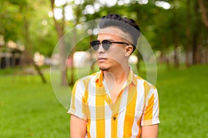 Young handsome multi ethnic man wearing sunglasses at the park outdoors