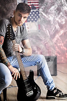 Young handsome musician with electric guitar on dark background