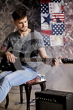 Young handsome musician playing electric guitar on dark background