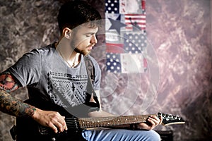 Young handsome musician playing electric guitar on dark background