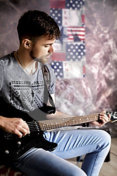 Young handsome musician playing electric guitar on dark background