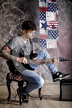 Young handsome musician playing electric guitar on dark background