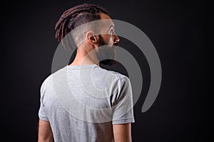Young handsome Persian man with dreadlocks against black background