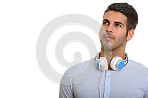 Young handsome Persian man thinking while wearing headphones aro