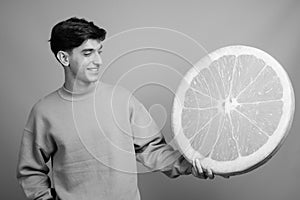 Young handsome Persian teenage boy against gray background