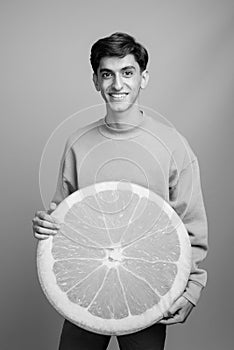 Young handsome Persian teenage boy against gray background