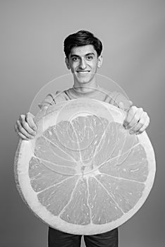 Young handsome Persian teenage boy against gray background