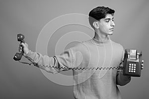 Young handsome Persian teenage boy against gray background