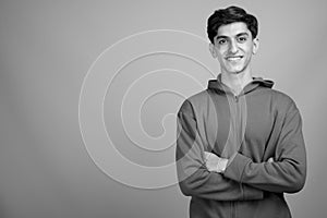 Young handsome Persian teenage boy against gray background