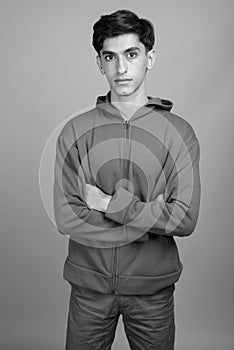 Young handsome Persian teenage boy against gray background