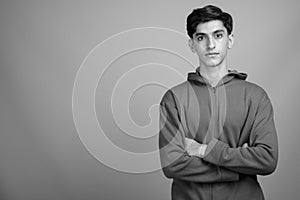 Young handsome Persian teenage boy against gray background