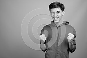 Young handsome Persian teenage boy against gray background