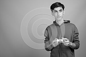 Young handsome Persian teenage boy against gray background