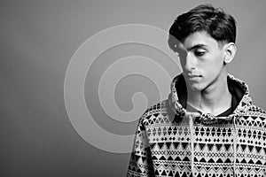 Young handsome Persian teenage boy against gray background