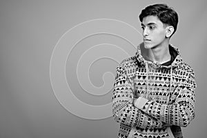 Young handsome Persian teenage boy against gray background