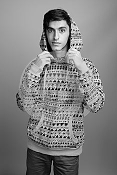 Young handsome Persian teenage boy against gray background