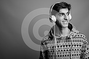 Young handsome Persian teenage boy against gray background