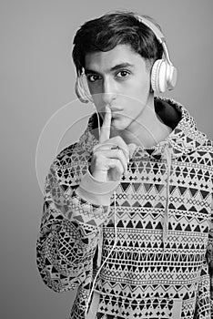 Young handsome Persian teenage boy against gray background