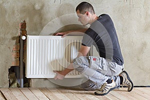 Young handsome professional plumber worker installing heating ra