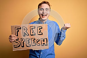 Young handsome redhead man asking for freedom holding banner with free speech message screaming proud, celebrating victory and