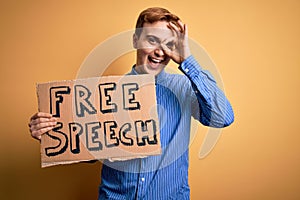 Young handsome redhead man asking for freedom holding banner with free speech message smiling happy doing ok sign with hand on eye