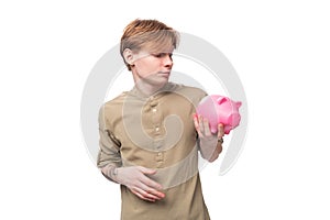 young handsome redhead student man holding piggy bank with savings