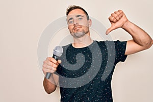 Young handsome singer man with blue eyes singing using microphone over white background with angry face, negative sign showing