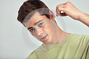 Young handsome smiling guy with brown hair applies beauty serum to his face to keep his skin soft and smooth