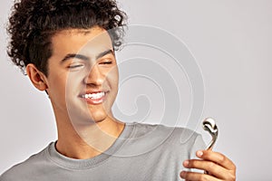 Young handsome smiling guy using de-puffing face roller to keep his skin soft and smooth. Swarthy man with black